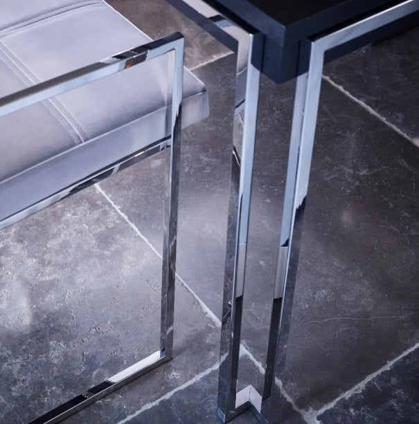 Close-up of a modern glass table with metal legs on a dark stone floor.